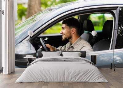 Young man pushing horn while driving sitting of a steering wheel press car, honking sound Wall mural